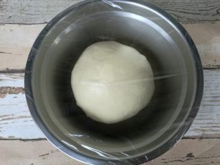 超好吃奶黄餐包,面团收圆，放盆内该保鲜膜进行基础发酵。