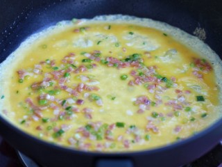 芝士培根鸡蛋卷,不粘锅中放少许油烧热后，倒入1/3的蛋液