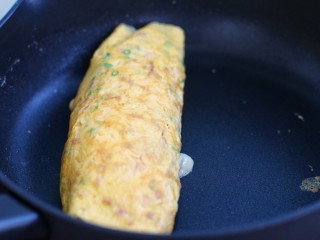 芝士培根鸡蛋卷,依照上面步骤把蛋卷再卷回来，两面稍微煎一下，出锅后切块食用即可