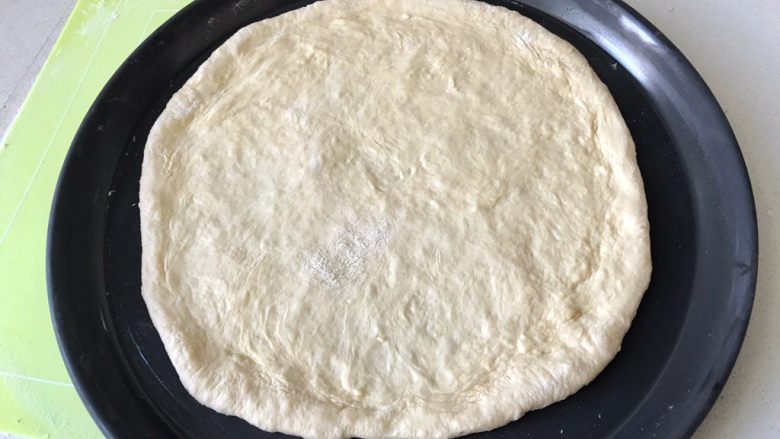 蘑菇披薩,然後將撑好的餅皮，放在抹好黃油的披薩烤盤上，在烤盤上也可以進一步做整形，盡量讓餅變圓一些