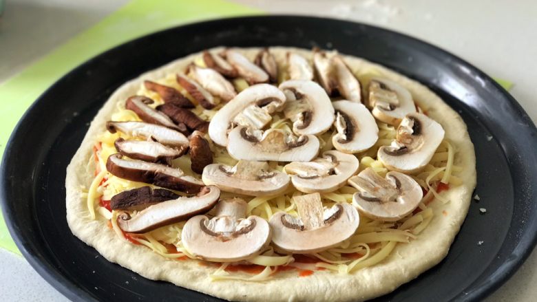 蘑菇披薩,將蘑菇片擺在奶酪絲上面