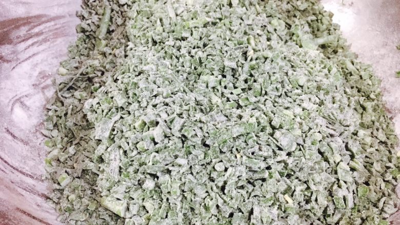 韭菜小圆子,分三次，每次放入一把面粉，把它们和匀，和好后每粒韭菜都沾上了一层薄薄的面粉。