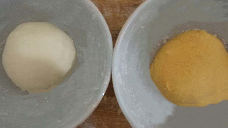 南瓜包子,﻿﻿揉成两个面团，﻿裹上薄薄的一层面粉，用保鲜膜盖住，发酵﻿﻿﻿﻿﻿