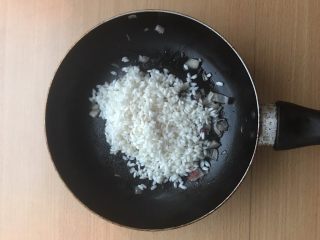 土豆苹果炖饭,加入生米。稍微炒一会，让培根香气进入大米中。