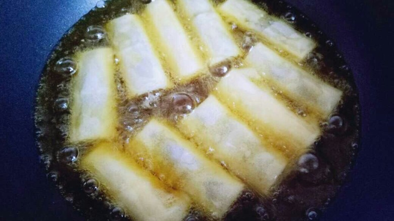 炸春卷,炸锅中放入食用油，油温8成时用筷子夹入包好的春卷。