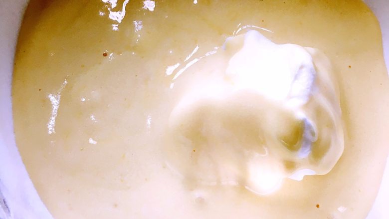 完美戚风蛋糕攻略,将9中蛋黄与蛋白混合物倒入剩下的蛋白中，注意倒入时尽量让蛋黄液均匀地铺在剩下的蛋白上，在一个位置上倒入蛋黄液很可能沉入盆底，不易翻拌均匀