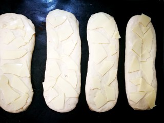 佛卡夏面包,二次发酵好，是原来的两倍大，开始撒顶部的料了，先把芝士片撕碎放上，如图。