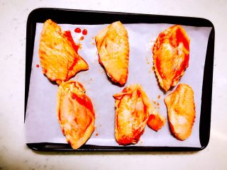 自制新奥尔良烤翅,将腌制好的鸡中翅放上垫好油纸的烤盘中，同时提前预热烤箱，200度10分钟