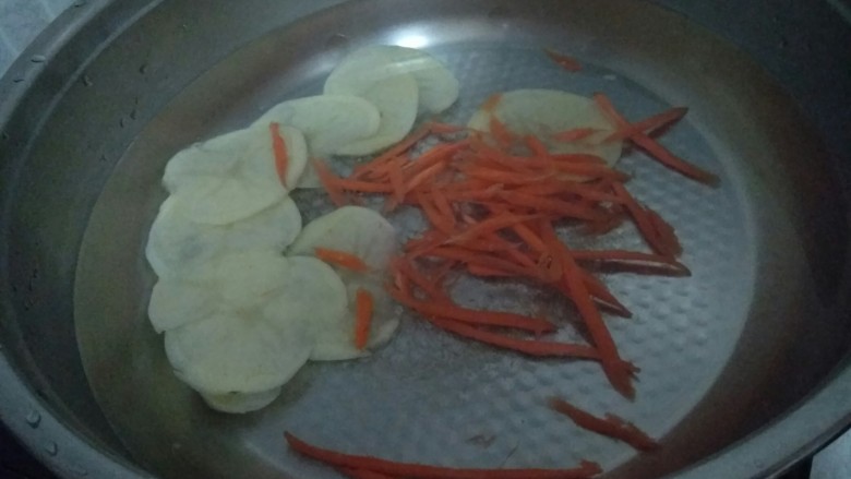 东北双人份麻辣拌之酸甜拌,锅里倒入凉水开始先放入比较难熟的土豆片和胡萝卜丝。