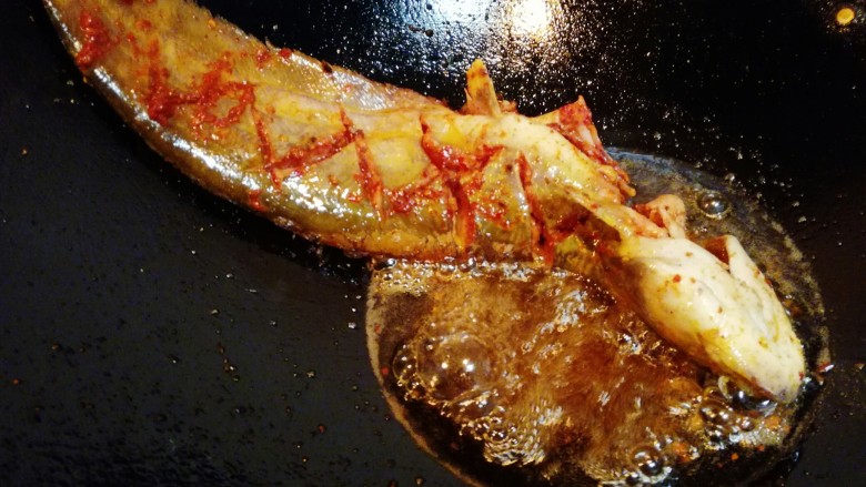 豆豉烤鱼,将鱼放入锅中油炸，油炸期间，不停的将滚油浇在鱼身上。