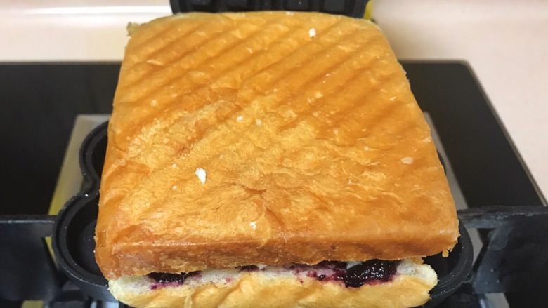 快手早餐帕尼尼,把准备好的三明治放在华夫饼机上面。