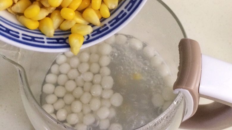 玉米圆子甜酒酿,圆子煮熟浮起来时，就可以倒入玉米粒。