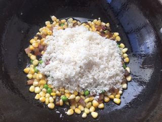 土豆腊肉焖饭,玉米粒，豌豆翻炒大概2分钟，添加大米一起翻炒。