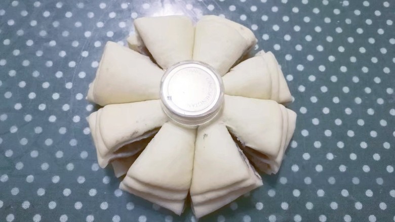 花式豆沙面包,找个合适的小瓶盖放在叠加的面皮中间，然后沿着瓶盖四周用刀切割成均匀的8等份；
