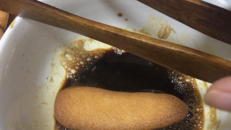提拉米苏蛋糕,拇指饼干在咖啡酒中翻滚一圈，取出放入8寸蛋糕容器中