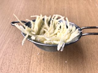 土豆鸟巢和溏心蛋宝宝,用一个漏勺上面铺上土豆丝，尽量贴着边缘铺，形成一个碗状。