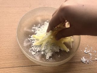 土豆鸟巢和溏心蛋宝宝,在一个盘子中放一些生粉。汆完水的土豆丝放进去稍微抓一抓。