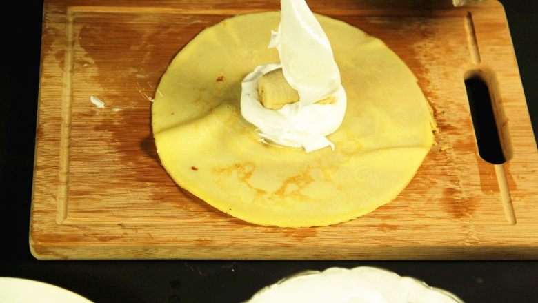 经典港式甜品——香蕉班戟（独家配方）,取一张面饼，在面饼的中间铺上一层奶油，上面放上香蕉段，然后再加一层奶油