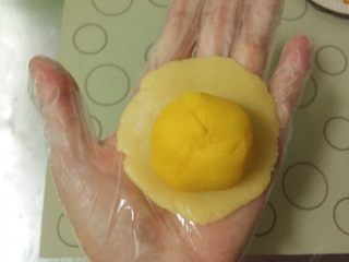 金沙奶黄月饼,取一个奶黄馅放到饼皮中间，用虎口慢慢将饼皮向中间推，整理好收口，防止露馅