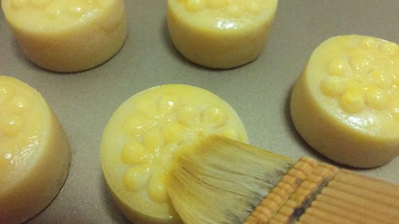 金沙奶黄月饼,待花纹定型后，取出来刷一层薄薄的蛋黄液，接着烤15分钟，最好中间再取出来刷一次蛋黄液