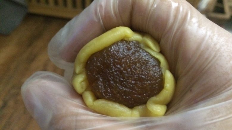 五彩桃山皮月饼,用虎口慢慢推，如果皮有点干，可以在手套上抹上一点点油，防止裂开。
