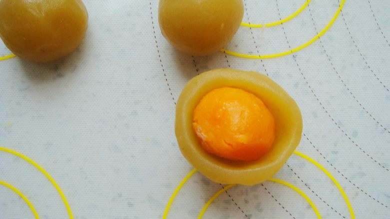 广式莲蓉蛋黄月饼,莲蓉馅在手心里按扁，包入一颗咸蛋黄。
