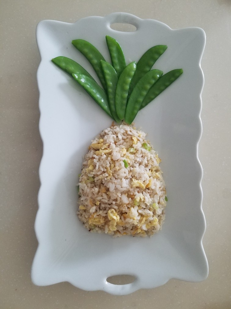 菠萝蛋包饭,炒好的米饭盛到盘子里，用勺子整形成菠萝的形状，上窄下宽。
