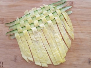 菠萝蛋包饭,然后把蛋条放下，错开上一排继续间隔一个揭起鸡蛋条再放入黄瓜条。