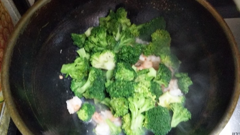 虾炒绿菜花,倒入少许盐，把蒜放进去炒匀