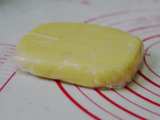 黄桃乳酪派,面团移至揉面垫，撒少许手粉，分成均等的两份，整形成方形，厚度2cm。用保鲜膜包好，放入冰箱冷藏一夜。（做好的派皮面团是400g，我们用到的面