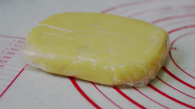 黄桃乳酪派,面团移至揉面垫，撒少许手粉，分成均等的两份，整形成方形，厚度2cm。用保鲜膜包好，放入冰箱冷藏一夜。（做好的派皮面团是400g，我们用到的面