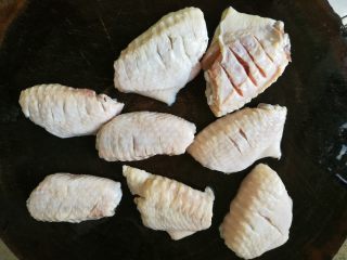 麻辣鸡翅煲,3、	捞出，沥干水，鸡翅表面割上几刀，以便入味。