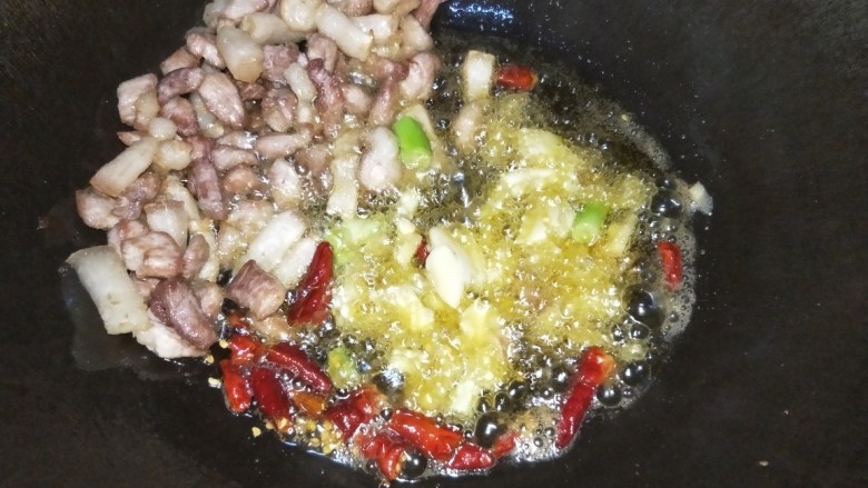 芋儿烧肉,把猪肉拨到一边放入生姜、蒜、干辣椒、葱段爆香