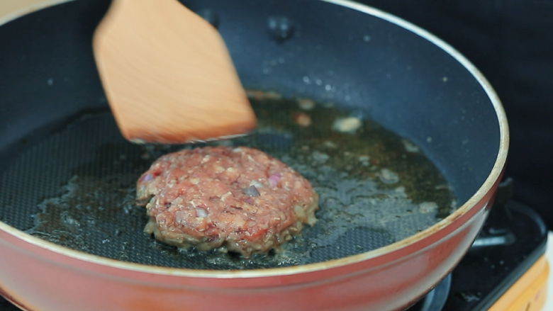 牛肉汉堡,平底锅倒入调和油，油烧到七成热，把肉饼放入炸至焦黄。可以轻轻用锅铲压一压肉饼，让饼的形状更牢固，不容易散开。