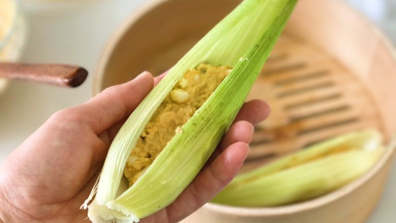 無面粉粗粮玉米餎,然後將玉米泥小心地放入清洗過的玉米葉子里，輕輕的裹起來，不要露出玉米，這樣在蒸的時候可以充分裹住玉米的味道。葉子長出的部分可以稍稍剪掉一些。