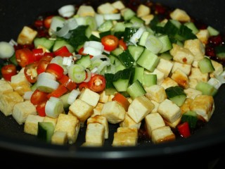 美味下饭宫保豆腐,豆腐丁、黄瓜丁、葱段和红椒圈依次入锅，快速翻炒均匀。