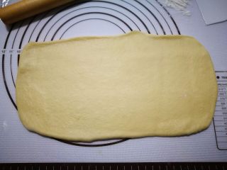 奶香法棍型面包,拿一个面团用擀面仗擀成长方形，上面那边稍微薄一点