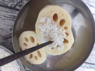 玫桂冰糖糯米藕,把泡好的糯米用筷子辅助添到藕眼中，注意要添实