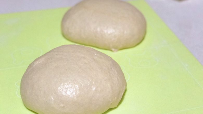肉桂核桃面包卷,將面團拿出來壓扁排氣，然後均勻地分成兩個面團，揉勻滾圓醒面20分鐘。