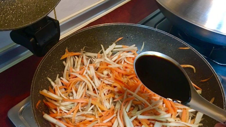 日式牛蒡炒胡蘿蔔絲,打開鍋蓋加入醬油拌炒