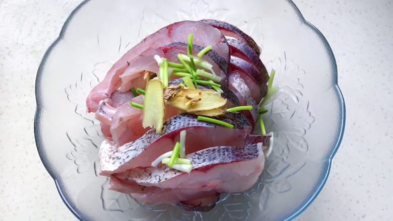 秘制酥鱼,把鱼肉放进容器里，撒上葱白和姜片
