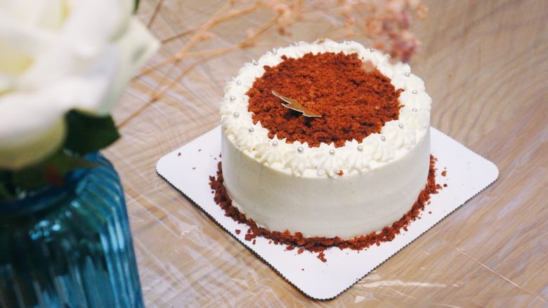 红丝绒奶油奶酪蛋糕,最后用裱花嘴在周围做简单装饰，再撒上红丝绒蛋糕屑即可。