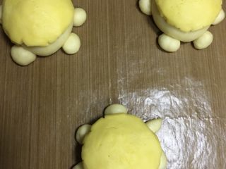 萌小龟面包,把冷藏过的酥皮取出，平均分成八份，用几个取几个搓圆，压扁盖在乌龟背上，进行二次发酵，发酵时要放热水