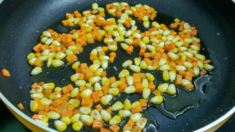 玉米火腿蛋炒饭,放入玉米和胡萝卜翻炒至快熟。