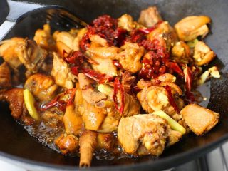 新疆大盘鸡,放入姜蒜、少许醋炒匀，接着放入花椒粒、干辣椒、八角、桂皮炒匀；