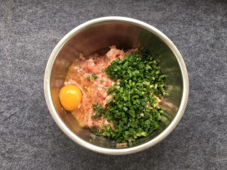 韭菜蒸饺子,鸡蛋一个磕入盘中，添加鸡蛋可以增加嫩滑口感！