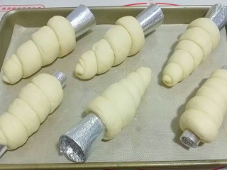 紫薯芋泥螺卷包,依次做完所有的螺卷摆入烤盘，盖保鲜膜进行二发；