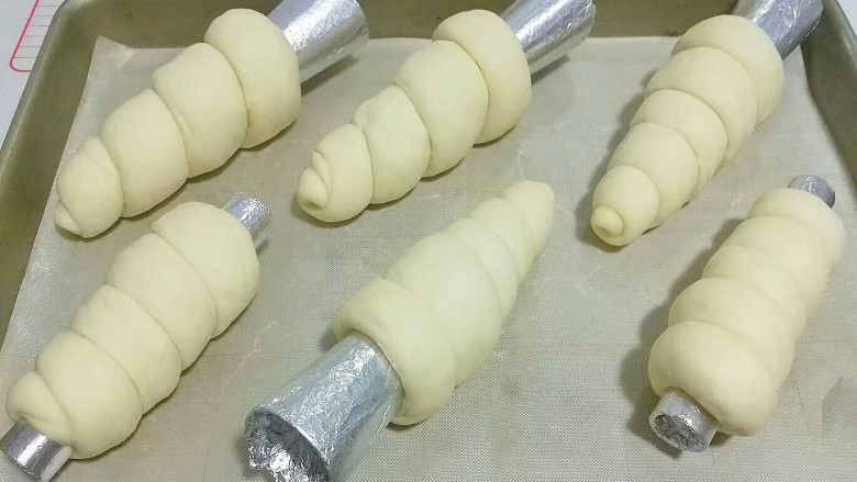 紫薯芋泥螺卷包,依次做完所有的螺卷摆入烤盘，盖保鲜膜进行二发；