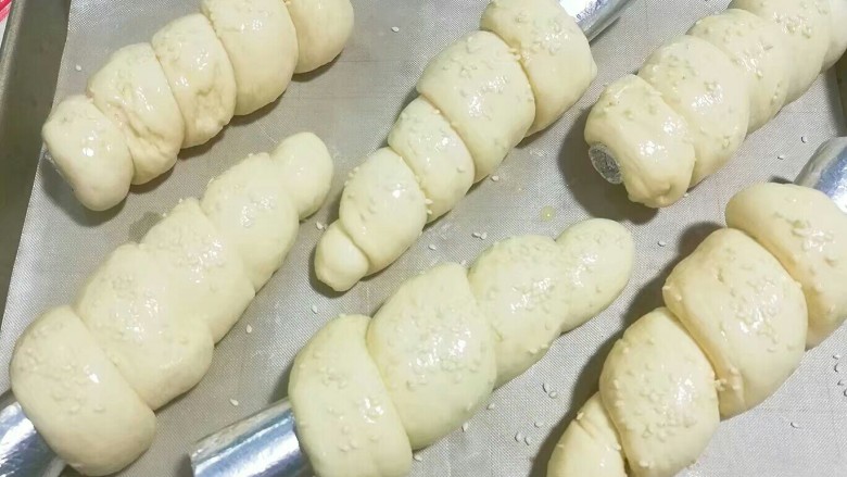 紫薯芋泥螺卷包,将发酵好的面包胚取出，刷上一层蛋液再洒点白芝麻，放入预热好的烤箱中层上下火170度烤约15~20分钟即好； 