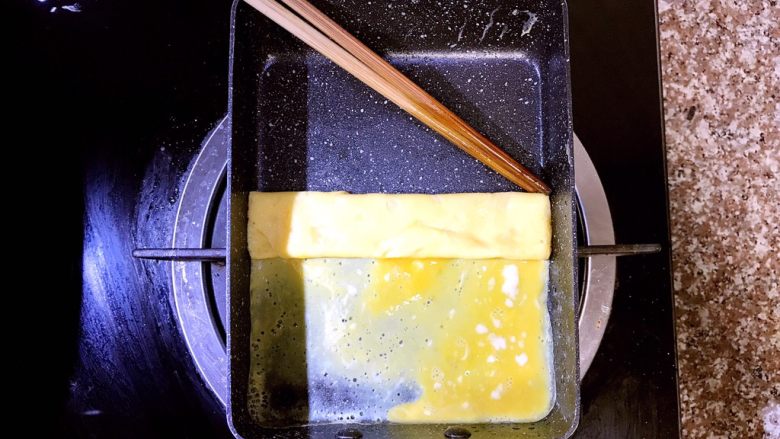日式厚蛋烧,待蛋液底层成型，但表面还未完全熟的时候用筷子小心的从上往下开始内卷。里层未完全熟的蛋液能把蛋饼牢牢粘住，不会松散，后面的操作会把蛋液全部煎熟的，不用担心